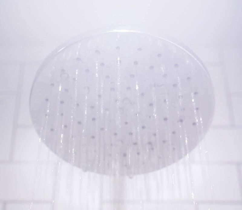 water from round gray stainless steel shower head